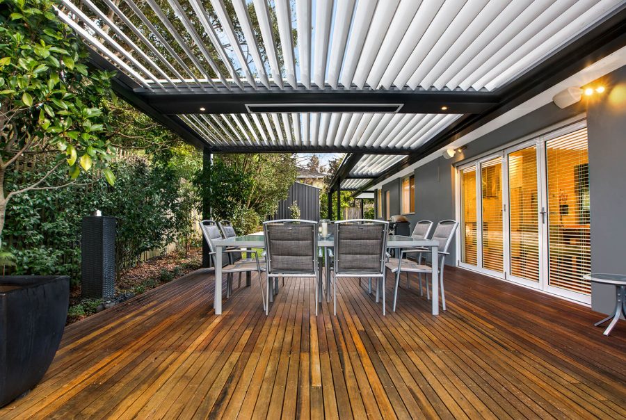 Modern custom opening louvred roof patio system and timber deck extension in St Ives, featuring an integrated flush ceiling heater, downlights, and a large outdoor dining area.