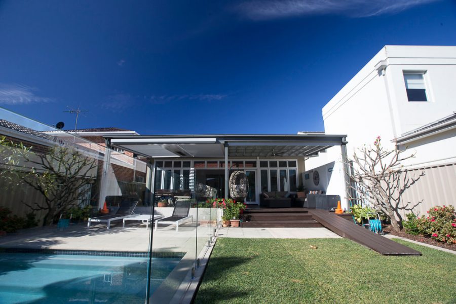 Custom opening louvred roof patio system and multi-level timber deck in Sans Souci, featuring a dark aluminium pavilion frame, glass pool fencing, and a custom timber accessibility ramp.
