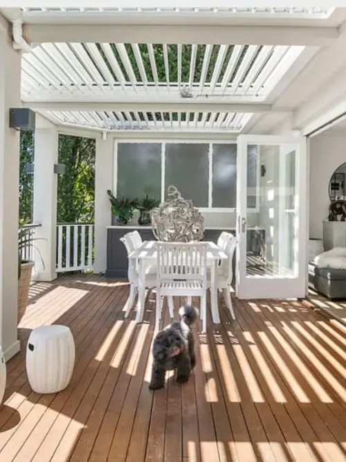 Stylish Northern Beaches patio featuring elevated deck, glass balustrades, and tranquil bushland views for refined outdoor entertaining.