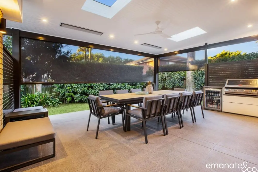 Contemporary alfresco room with integrated outdoor kitchen, louvre roof, and ambient lighting for all-season dining and relaxation.