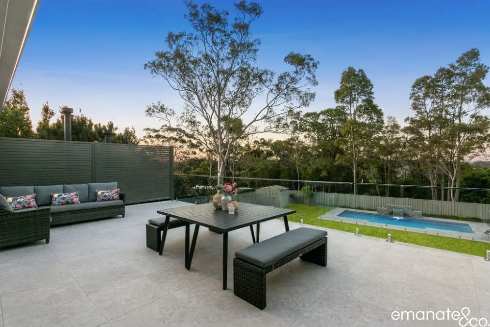Alfresco tiled patio with outdoor seating and dining area overlooking a fenced pool and lawn.