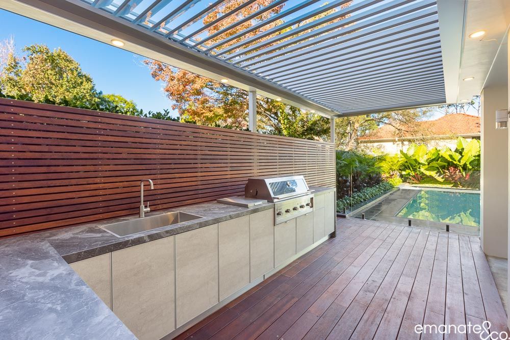 Outdoor kitchen on a Merbau hardwood timber deck next to a pool under an opening roof patio cover in Wahroonga