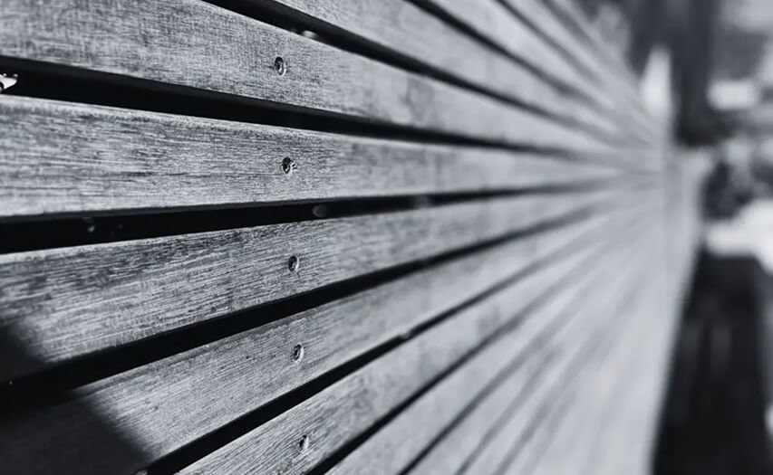 Close-up grayscale detail of a custom timber privacy screen and premium deck cladding installation featuring precision carpentry by Emanate and Co.