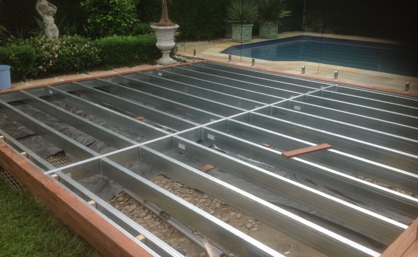 Low-to-ground deck engineering by Emanate and Co featuring a precision-leveled galvanized steel subframe joist grid installed next to a residential swimming pool.