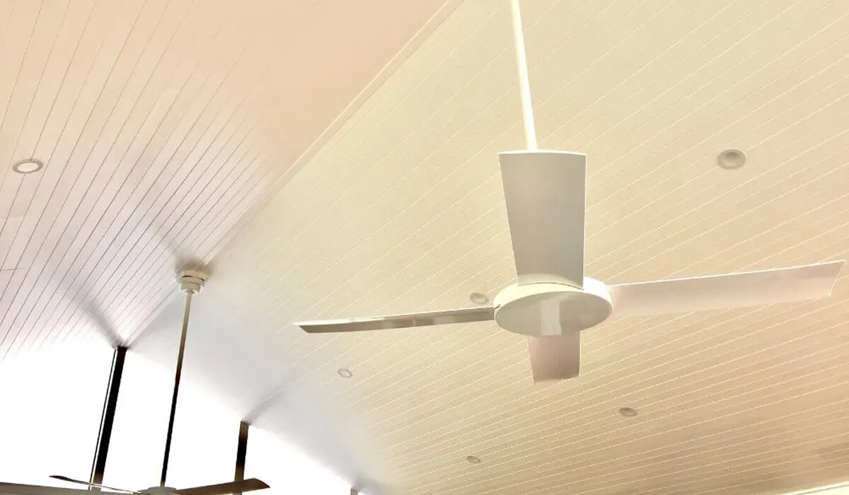 Luxury outdoor room design by Emanate Co showcasing a white timber V-groove lined patio ceiling with built-in skylights, sleek strip heaters, downlights, and a minimalist ceiling fan.