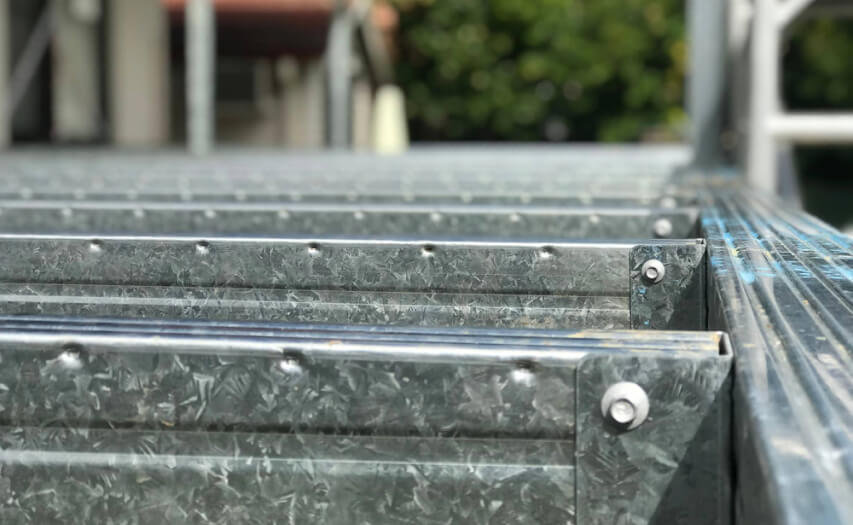 Close-up of a precision-engineered galvanized steel deck subframe joist system showing structural brackets and fasteners for a durable, rot-proof patio foundation.