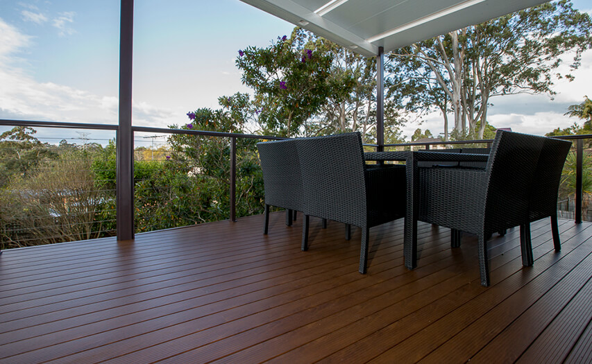 Premium non-combustible wood-look aluminium deck construction by Emanate and Co on the Northern Beaches, featuring black wicker alfresco furniture and a modern covered patio roof extension.