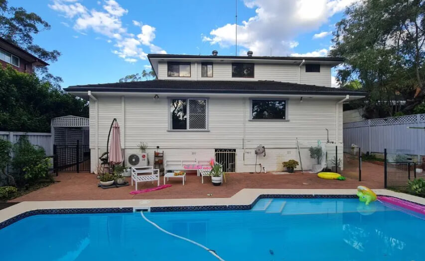 Original backyard site condition by Emanate and Co, showcasing an unshaded concrete patio and pool surround prior to a custom luxury alfresco room extension.