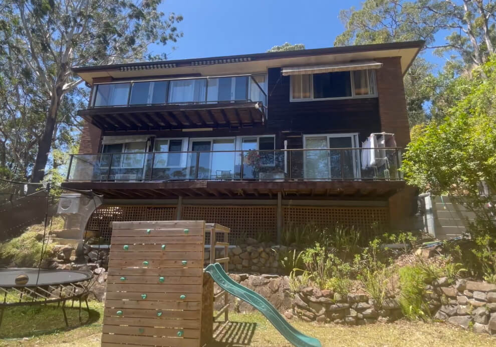 Original multi-tier timber deck and glass railings on a steep sloping block home prior to a complete architectural renovation by Emanate and Co.