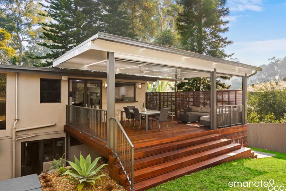 Elevated hardwood deck with broad garden steps, insulated skillion patio cover, dining and lounge zones at a leafy Sydney home.
