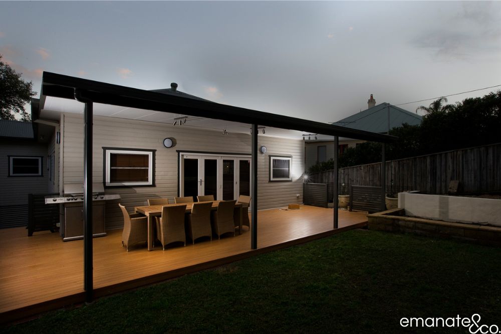 Illuminated insulated patio cover extending across a spacious timber deck, creating an all-weather outdoor dining and barbecue area for a Sydney home.