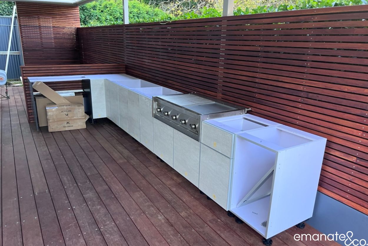 Custom outdoor kitchen cabinetry and built-in barbecue installation, framed by hardwood decking and timber privacy screening in Wahroonga.