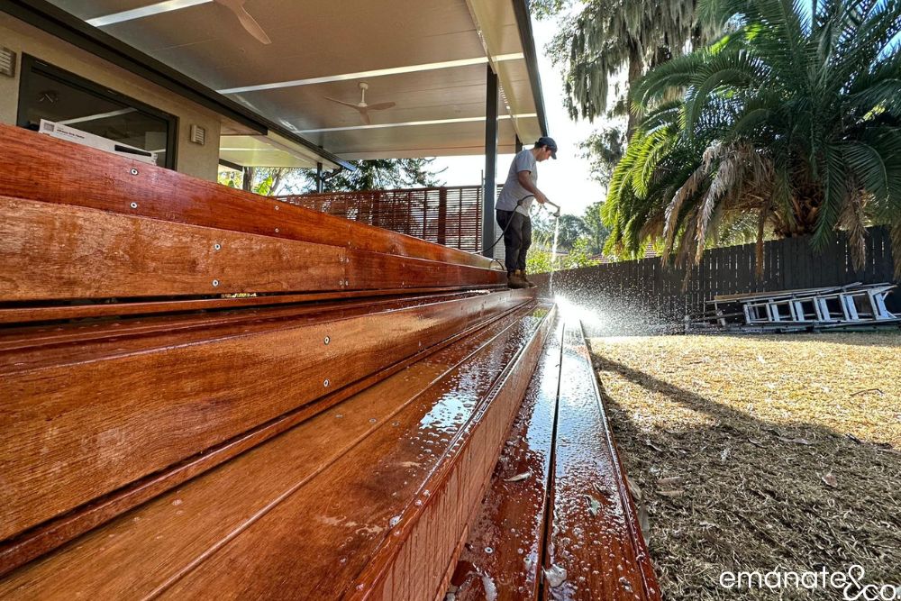 Emanate & Co. builder finishing broad hardwood deck steps beneath a custom insulated patio cover at this Normanhurst outdoor room.