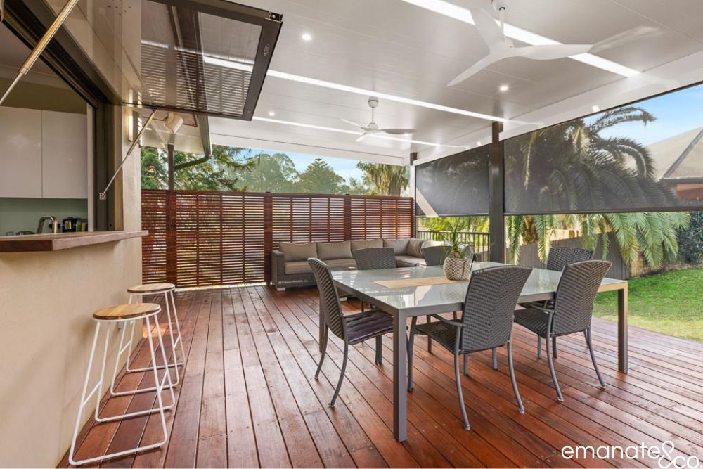 Premium Normanhurst alfresco with hardwood decking, outdoor dining, lounge seating, timber privacy screens, café servery and retractable weather blinds.