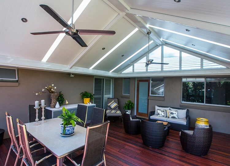 Spacious gabled insulated patio cover with skylights, ceiling fans, and outdoor furniture in Avalon by Emanate and Co.