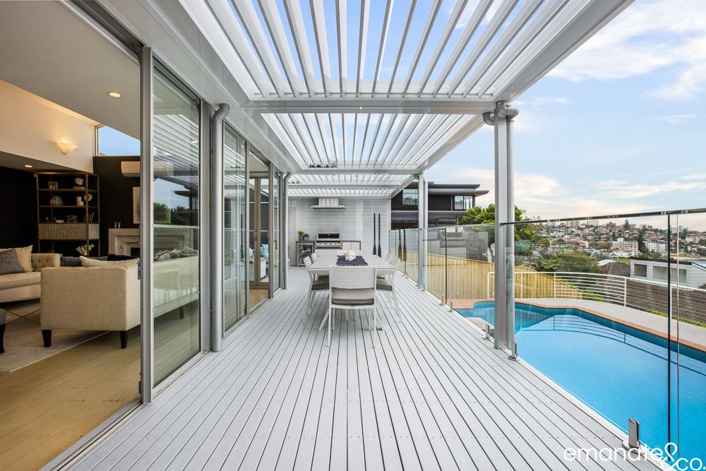 Harbourside alfresco with opening louvre roof, outdoor kitchen, glass balustrade and pool views, creating a premium Sydney outdoor entertaining space.