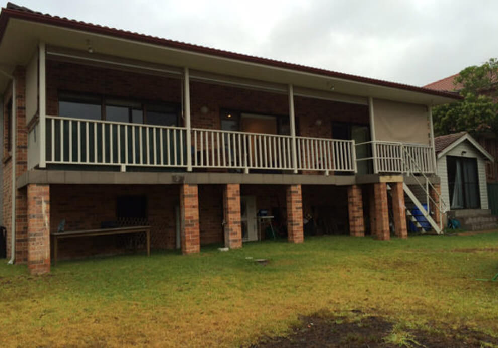 Elevated rear deck and balcony on brick piers before renovation by Emanate and Co.