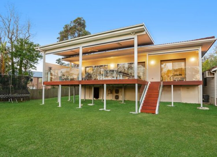 Elevated deck and flyover patio cover on steel posts with glass balustrade in West Pymble by Emanate and Co.