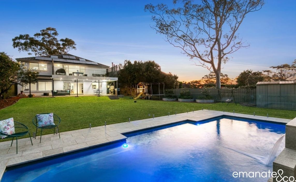 A luxurious backyard setting with a modern alfresco area, a well-lit patio, and a stunning pool, designed for stylish outdoor living.