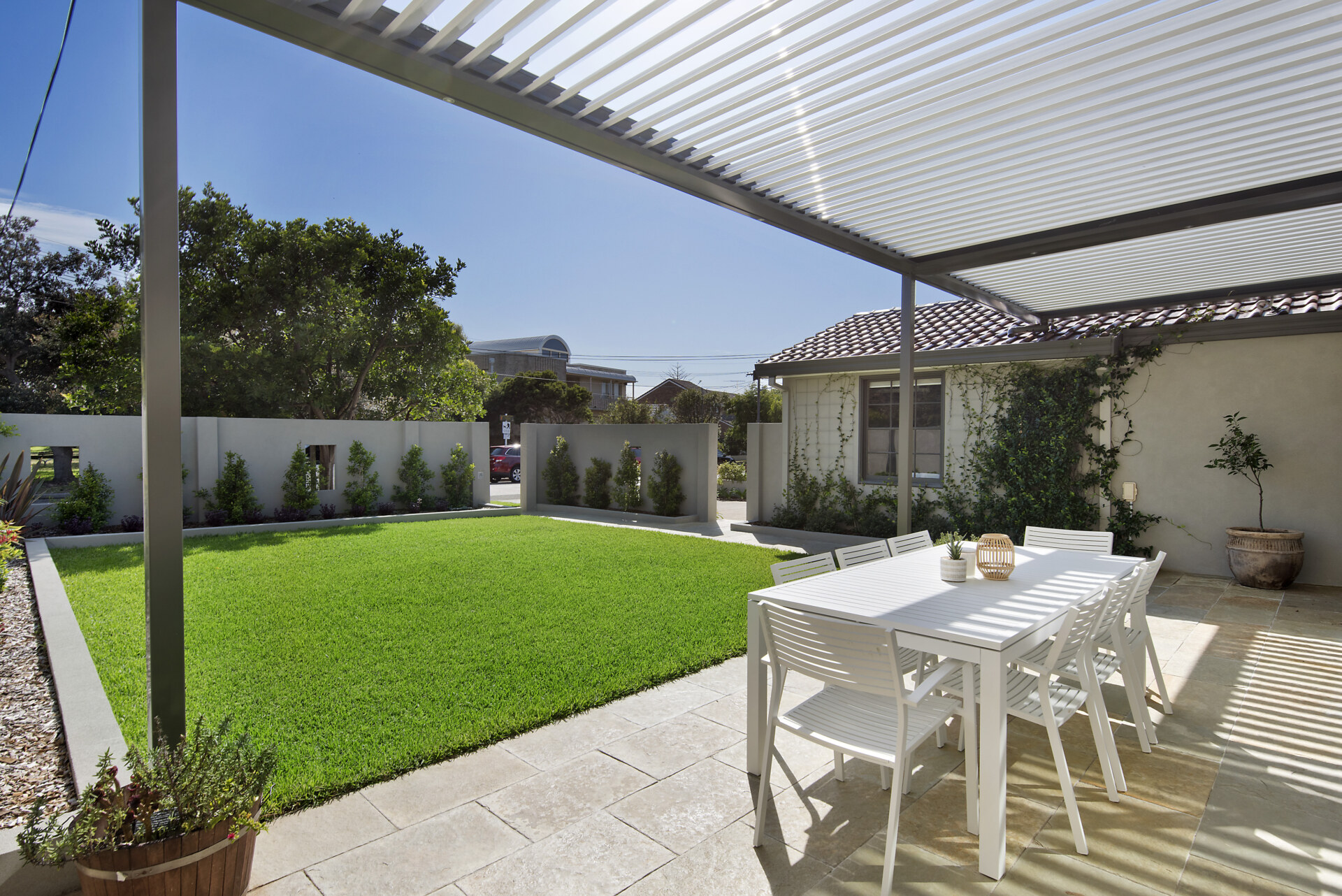 Spacious backyard with a louvred patio cover, alfresco dining area and lush green lawn.